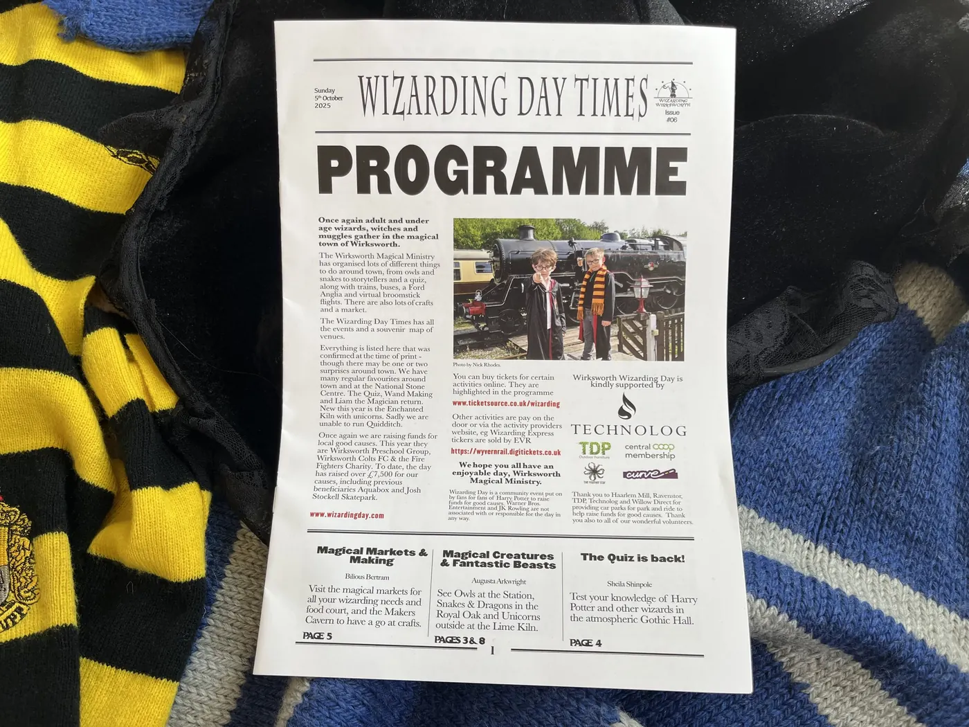 A copy of the Wizarding Day Times programme lying on a Hufflepuff scarf